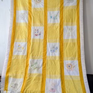 A vertical handmade crib quilt with a 4x7 grid pattern. It features alternating white squares with embroidered colorful animals—including lions, turtles, and puppies—and solid yellow squares with quilted floral designs. The blocks are separated by golden-yellow sashing and finished with a white ruffled border.