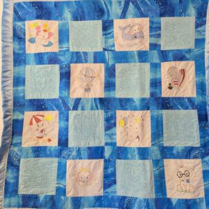 Blue quilt with embroidered animal designs.