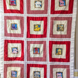 Handmade patchwork baby quilt featuring embroidered cartoon farm animals in windows, red and white gingham check squares, and a ruffled white satin border.