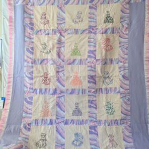 Quilt with embroidered doll designs and patterns.