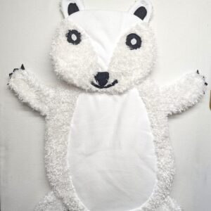 A handcrafted polar bear baby tummy time mat laid flat on a white surface, showing a smooth white fabric face and belly contrasted with a plush, curly white faux-fur textured trim on the head, arms, and legs. The bear features hand-stitched black eyes with white pupils, a black nose and mouth, and small black felt claws on its extended paws.